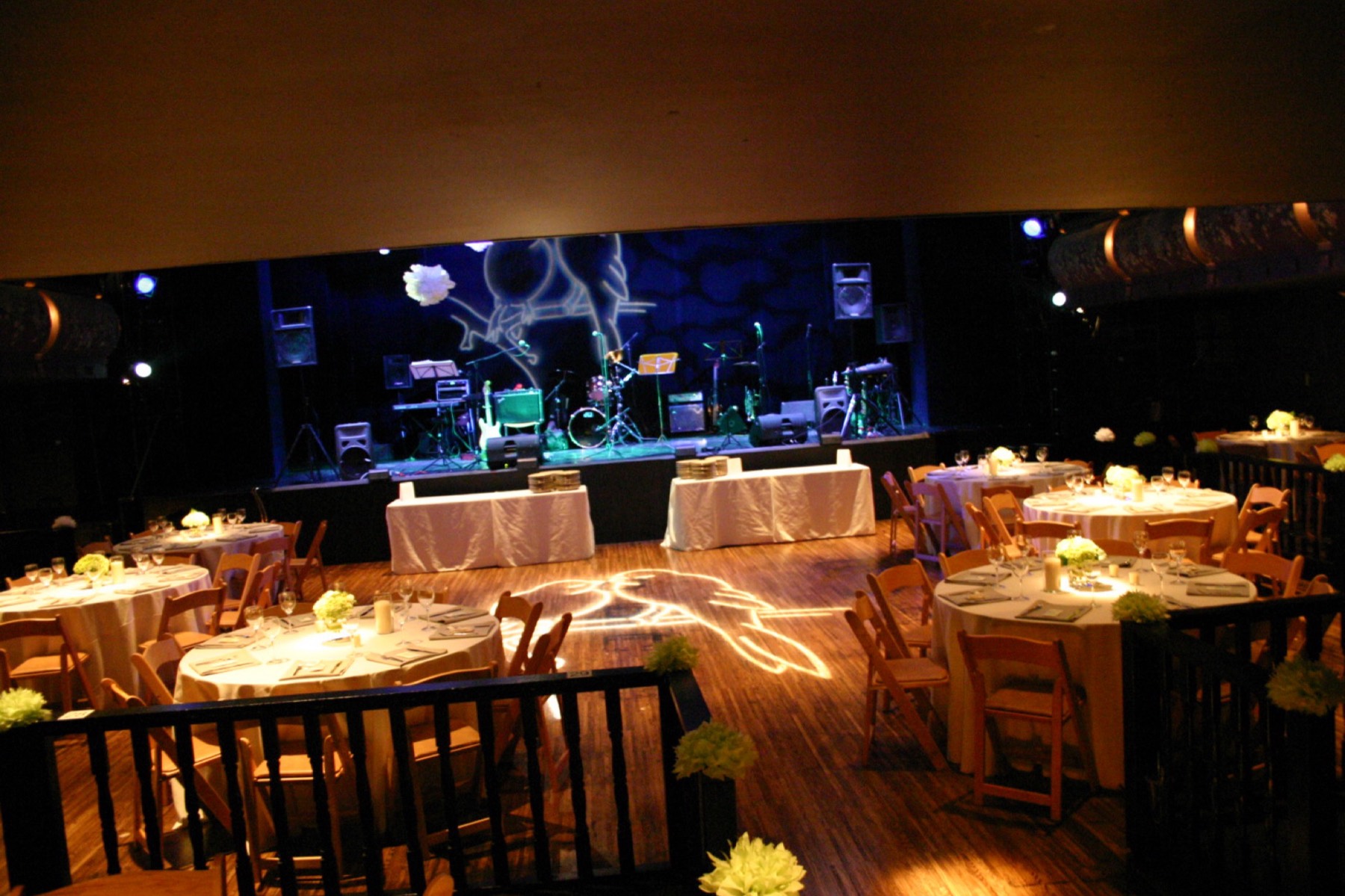 The auditorium set for a banquet, with a band on the lit stage and round tables across the floor